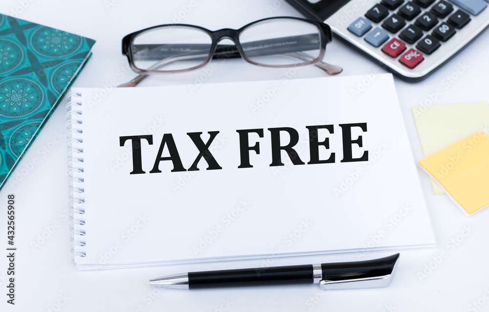 Tax Free text written in notepad beside glasses, calculator, pen on office desk Tax Free text written in notepad beside glasses, calculator, pen on office desk