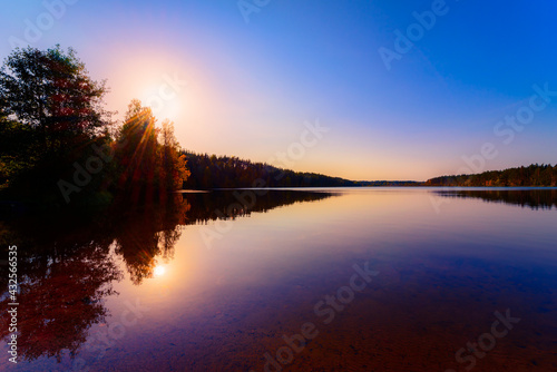 Sunset over the forest lake. View from the shore level