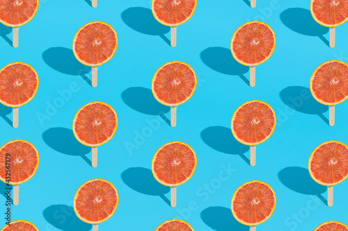 Creative Summer pattern background with red grapefruit and ice cream stick on a light blue background. Organic tropical fruit juice. Minimal summer food.