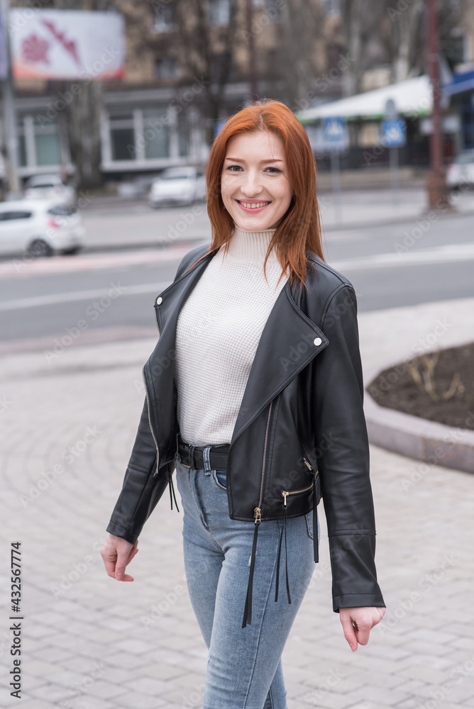 Fototapeta premium Portrait of a beautiful and positive redhead woman with clothes in grunge style. Posing while walking