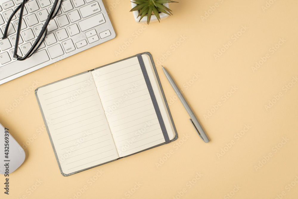 Top view photo of open grey organizer pen glasses white keyboard mouse and plant on isolated beige background with copyspace Top view photo of open grey organizer pen glasses white keyboard mouse and plant on isolated beige background with copyspace