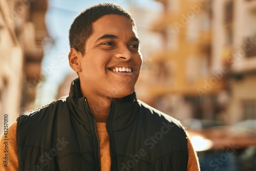 Young latin man smiling happy standing at the city