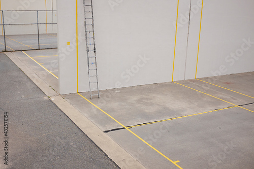 Grey concrete outdoor squash court with yellow lines