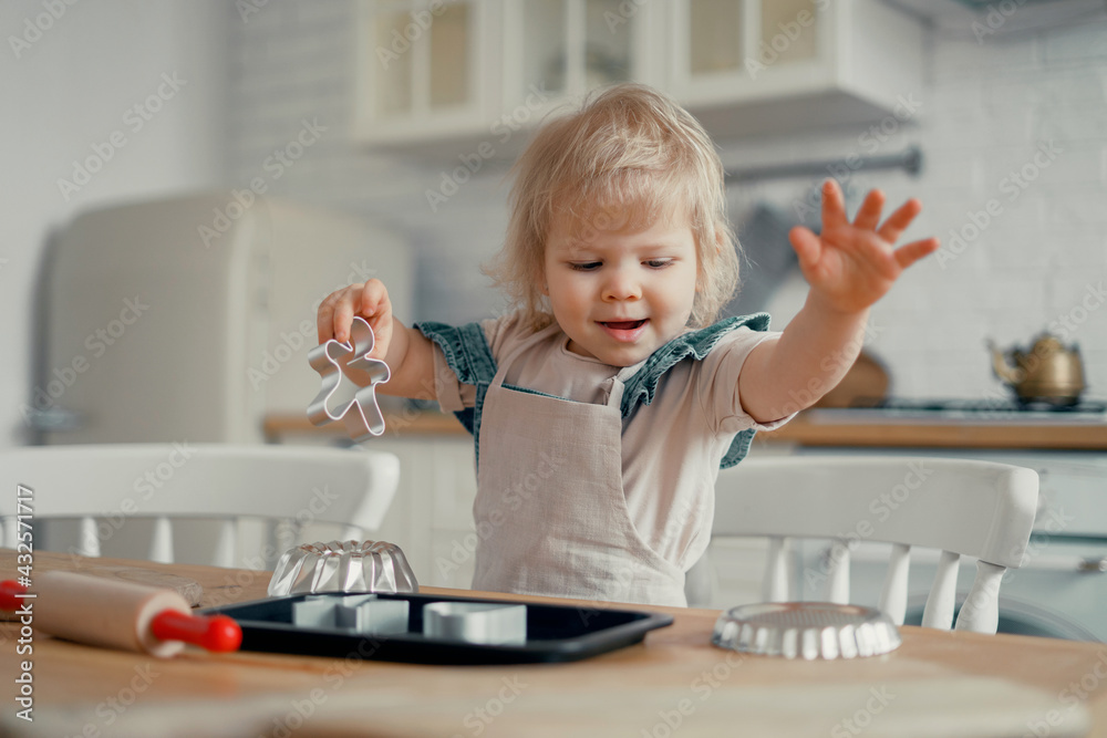 The little chef is the host on the table with the ingredients flour and sugar for a cake or sweet. Makes pastry dough, pasta, pizza, spaghetti, dessert. Baby girl playing in the kitchen. The little chef is the host on the table with the ingredients flour and sugar for a cake or sweet. Makes pastry dough, pasta, pizza, spaghetti, dessert. Baby girl playing in the kitchen.