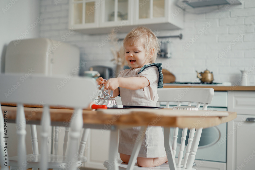 Girl cook cook in the kitchen. A small child plays with his mother on the table with the ingredients flour and sugar for a cake or sweet. Makes pastry dough, pasta, pizza, spaghetti, dessert. Girl cook cook in the kitchen. A small child plays with his mother on the table with the ingredients flour and sugar for a cake or sweet. Makes pastry dough, pasta, pizza, spaghetti, dessert.