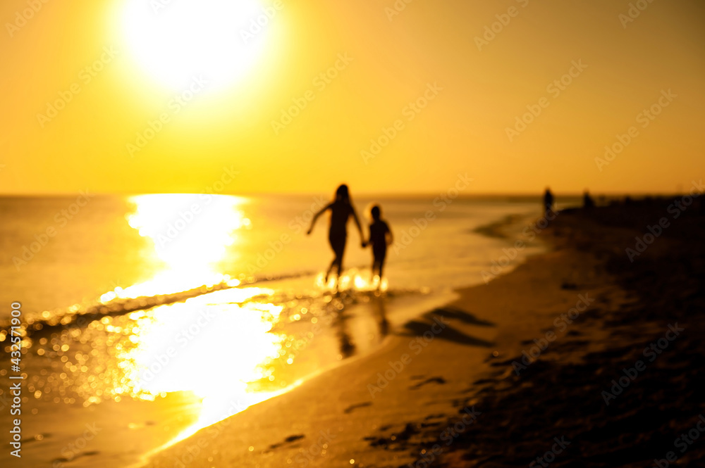 Silhouettes of two happy children playing and running along the seashore at sunset Silhouettes of two happy children playing and running along the seashore at sunset