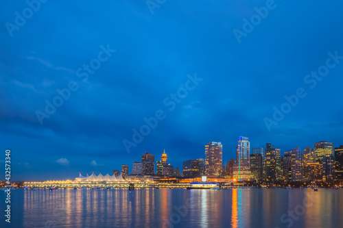 Urban illuminated cityscape skyline of downtown Vancouver, B.C. and Coal Harbour from Stanley park seawall at night during blue hour. photo