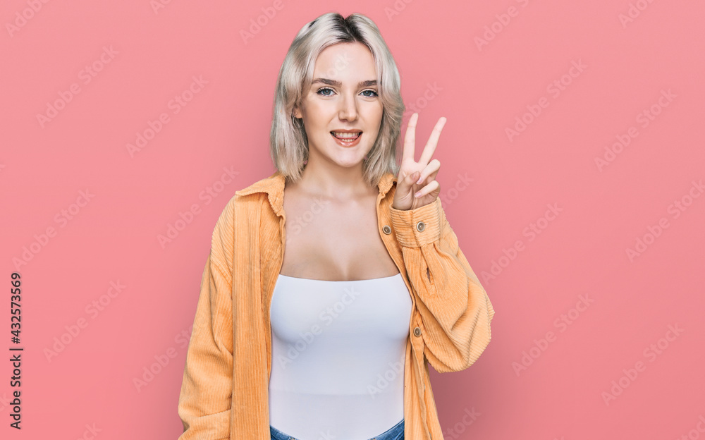 Young blonde girl wearing casual clothes smiling with happy face winking at the camera doing victory sign. number two. Young blonde girl wearing casual clothes smiling with happy face winking at the camera doing victory sign. number two.