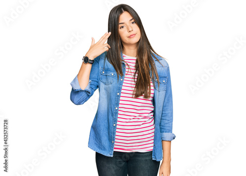 Canvas Print Young brunette woman wearing casual clothes shooting and killing oneself pointing hand and fingers to head like gun, suicide gesture
