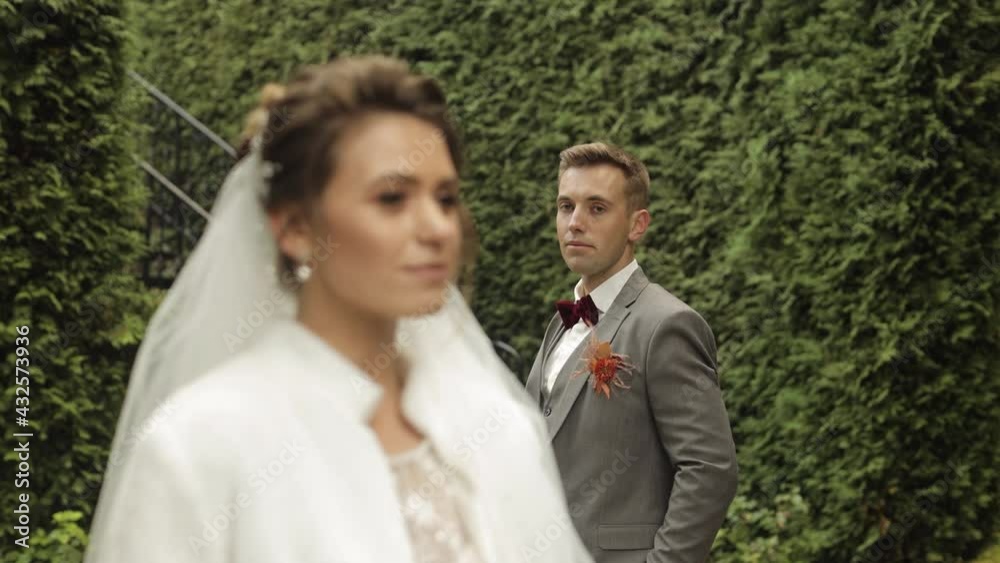 Newlyweds. Lovely young caucasian bride and groom stay in park. Happy wedding couple family. Man and woman in love. Summer. Bride in gorgeous luxury wedding dress. Bridegroom in jacket. Slow motion Newlyweds. Lovely young caucasian bride and groom stay in park. Happy wedding couple family. Man and woman in love. Summer. Bride in gorgeous luxury wedding dress. Bridegroom in jacket. Slow motion