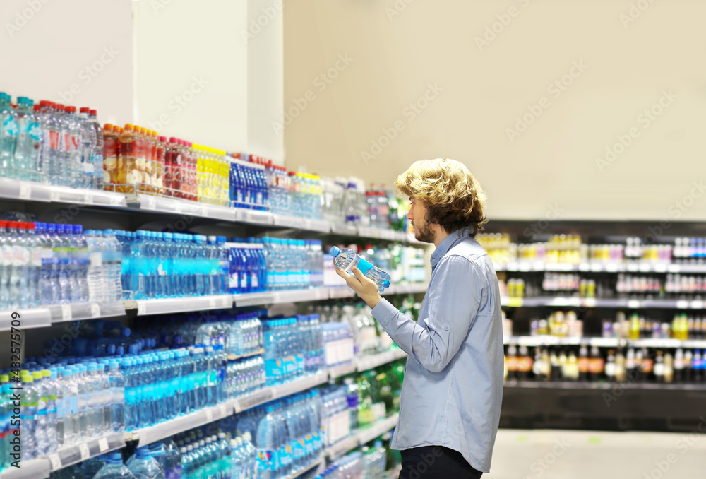 Young man shopping in supermarket, Buying a bottle of water in a supermarket