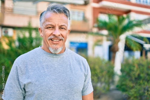 Slika na platnu Middle age hispanic grey-haired man smiling happy standing at the park
