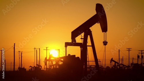 The sun rises behind oil pumps in California photo