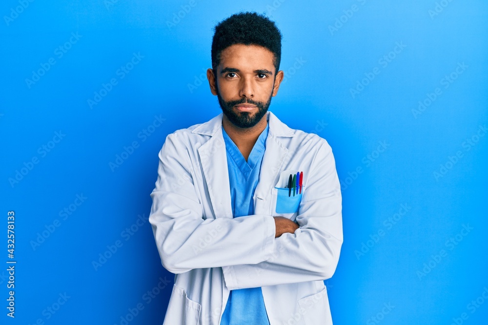 Handsome hispanic man with beard wearing doctor uniform skeptic and nervous, disapproving expression on face with crossed arms. negative person. Handsome hispanic man with beard wearing doctor uniform skeptic and nervous, disapproving expression on face with crossed arms. negative person.