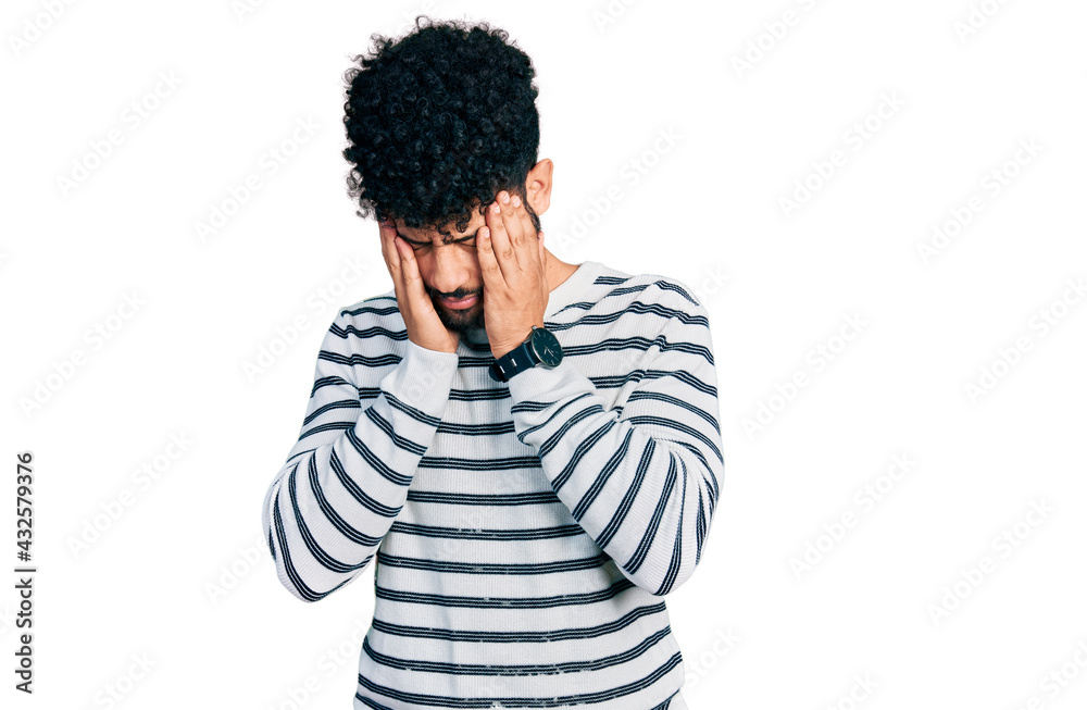 Young arab man with beard wearing casual striped sweater with hand on head, headache because stress. suffering migraine. Young arab man with beard wearing casual striped sweater with hand on head, headache because stress. suffering migraine.