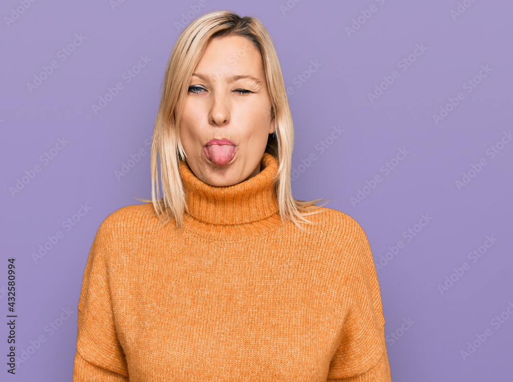 Middle age caucasian woman wearing casual winter sweater sticking tongue out happy with funny expression. emotion concept. Middle age caucasian woman wearing casual winter sweater sticking tongue out happy with funny expression. emotion concept.