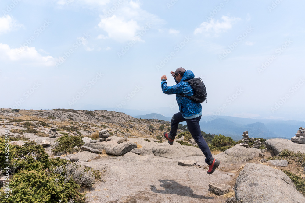 Obraz premium Hispanic hiker jumping up on mount Tlaloc under a cloudy sky in Mexico