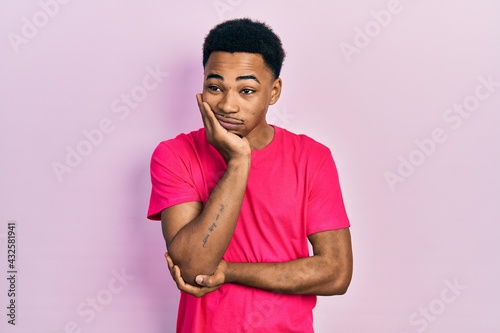 Young african american man wearing casua t shirt thinking looking tired and bored with depression problems with crossed arms.