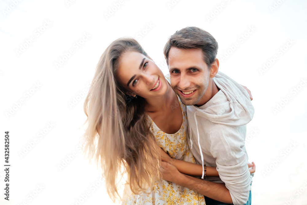 Young couple in love having fun. She is hugging him from the back. A guy carrying a girl on his back.