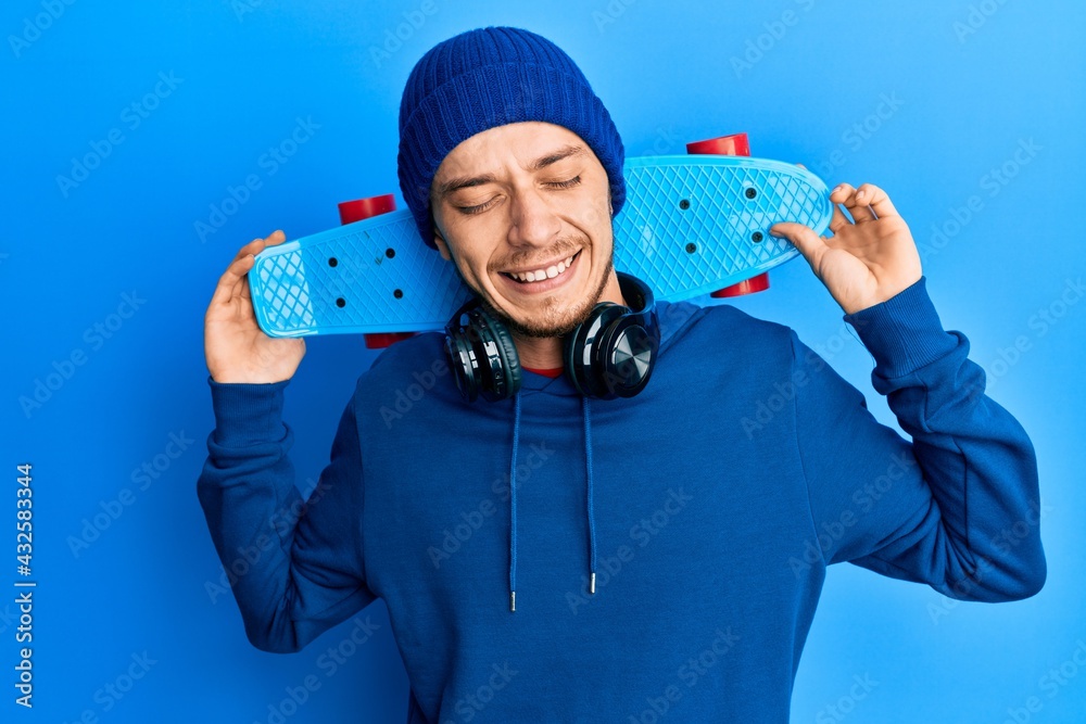 Hispanic young man holding skate smiling and laughing hard out loud because funny crazy joke. Hispanic young man holding skate smiling and laughing hard out loud because funny crazy joke.