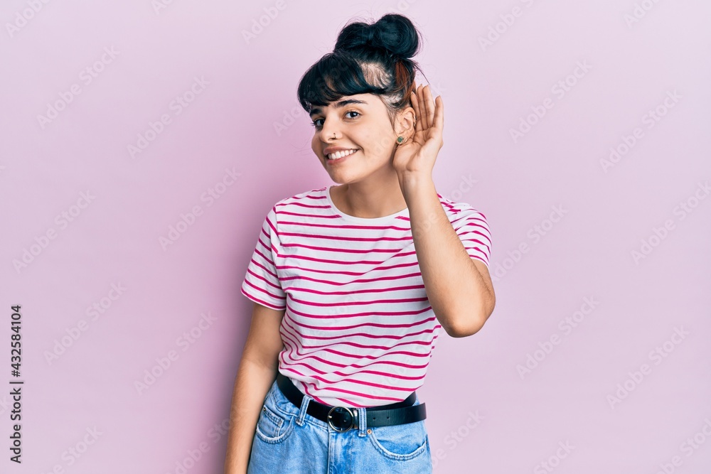 Young hispanic girl wearing casual clothes smiling with hand over ear listening an hearing to rumor or gossip. deafness concept. Young hispanic girl wearing casual clothes smiling with hand over ear listening an hearing to rumor or gossip. deafness concept.