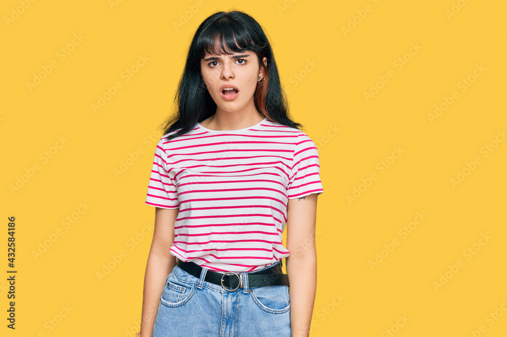 Young hispanic girl wearing casual clothes in shock face, looking skeptical and sarcastic, surprised with open mouth Young hispanic girl wearing casual clothes in shock face, looking skeptical and sarcastic, surprised with open mouth