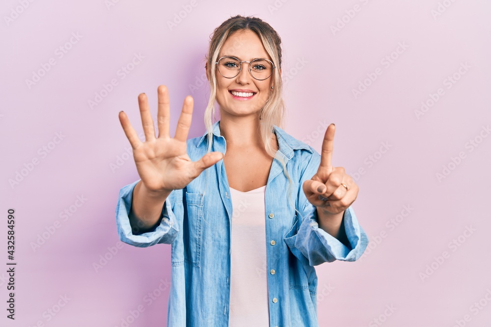 Beautiful young blonde woman wearing casual clothes and glasses showing and pointing up with fingers number six while smiling confident and happy.