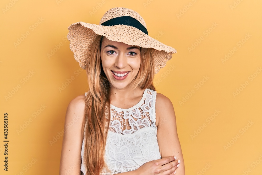 Young caucasian woman wearing summer hat happy face smiling with crossed arms looking at the camera. positive person. Young caucasian woman wearing summer hat happy face smiling with crossed arms looking at the camera. positive person.
