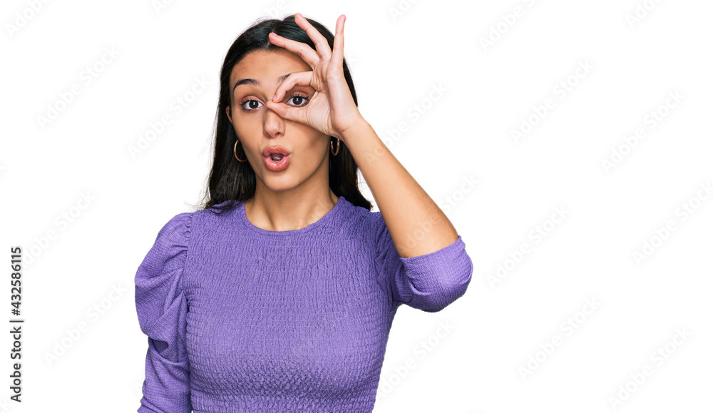 Young hispanic girl wearing casual clothes doing ok gesture shocked with surprised face, eye looking through fingers. unbelieving expression. Young hispanic girl wearing casual clothes doing ok gesture shocked with surprised face, eye looking through fingers. unbelieving expression.