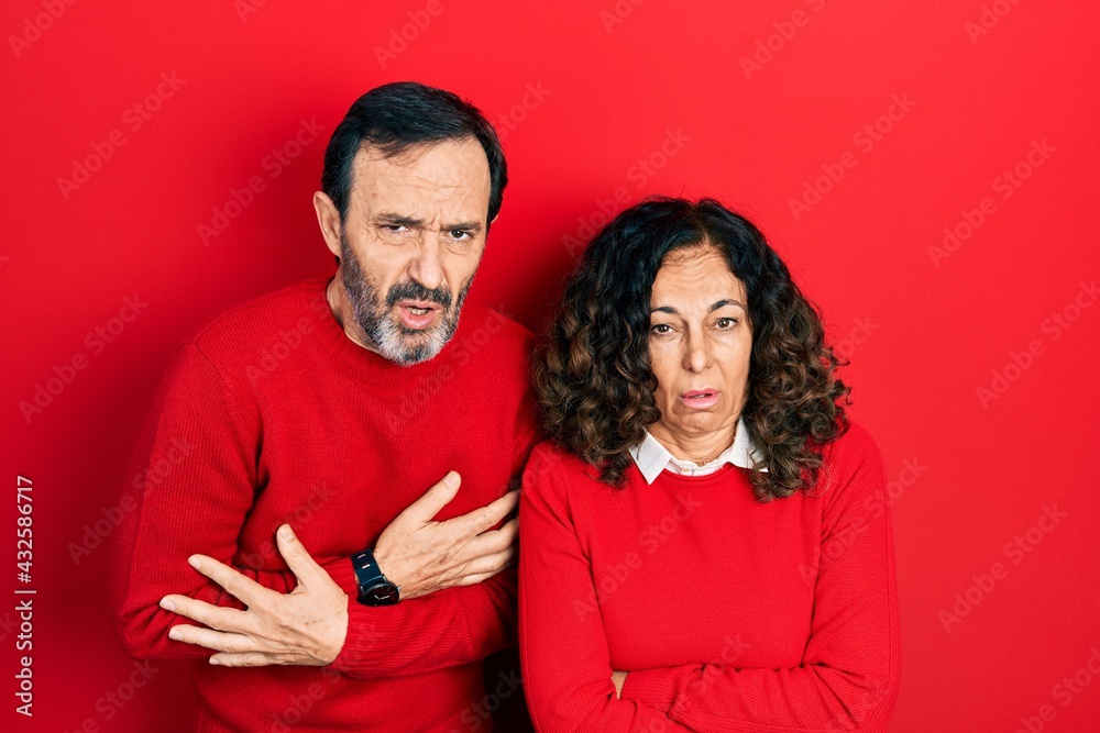 Fototapeta premium Middle age couple of hispanic woman and man hugging and standing together shaking and freezing for winter cold with sad and shock expression on face