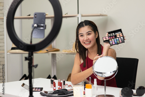 Beautiful Asian woman beauty makeup artist vlogger explain beauty cosmetic product on social media live streaming on smartphone. Online shopping business advertising by blogger or influencer concept.