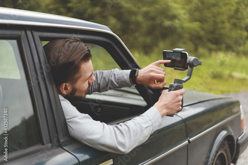 Side view of businessman films a travel photos using smartphone with steadycam photo