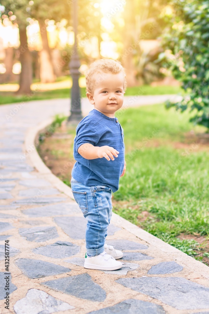 Cute and happy little boy having fun at the park on a sunny day. Beautiful blonde hair male toddler playing outdoors Cute and happy little boy having fun at the park on a sunny day. Beautiful blonde hair male toddler playing outdoors