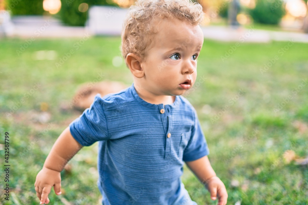 Cute and happy little boy having fun at the park on a sunny day. Beautiful blonde hair male toddler playing outdoors Cute and happy little boy having fun at the park on a sunny day. Beautiful blonde hair male toddler playing outdoors