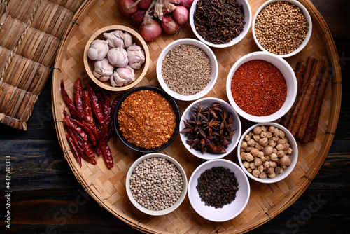 Fototapeta Naklejka Na Ścianę i Meble -  Various dry spices and herbs in a bowl on bamboo tray. Asian food ingredients (chili, clove, caraway, coriander seed, star anise, cardamom, pepper, cinnamon, garlic and shallot)