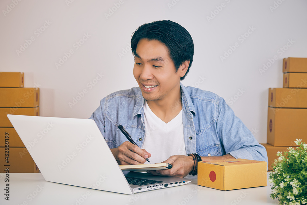 Online Merchant or Casual Businessman in Online Store Check Product Detail in Laptop and Writing Notebook in Vintage Tone Online Merchant or Casual Businessman in Online Store Check Product Detail in Laptop and Writing Notebook in Vintage Tone