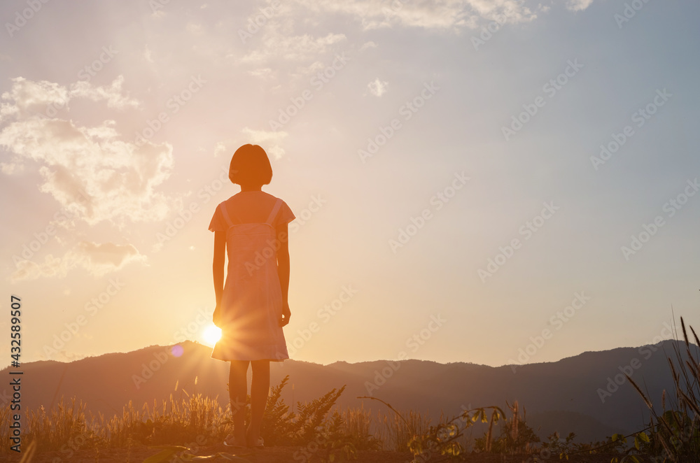 Silhouette of little girl standing on a background of gorgeous sunset
