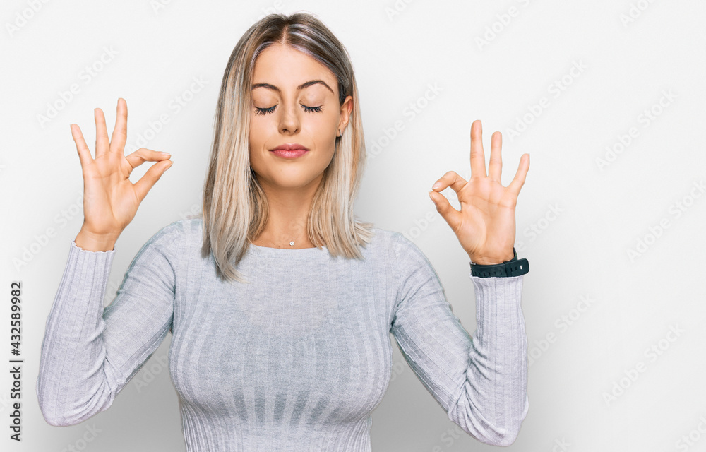 Beautiful blonde woman wearing casual clothes relaxed and smiling with eyes closed doing meditation gesture with fingers. yoga concept. Beautiful blonde woman wearing casual clothes relaxed and smiling with eyes closed doing meditation gesture with fingers. yoga concept.