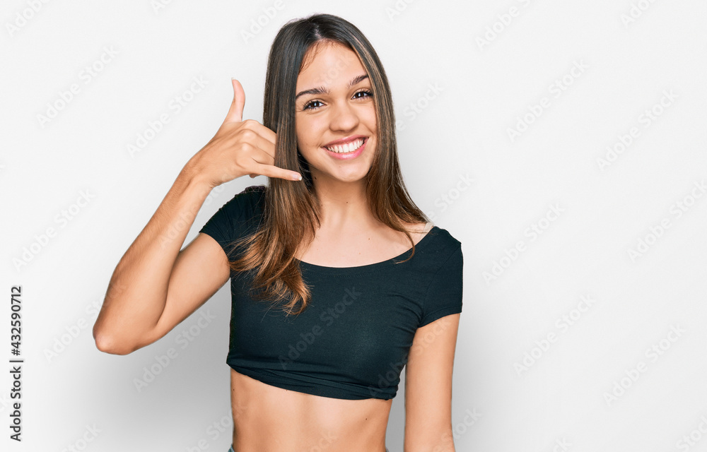 Young brunette woman wearing casual clothes smiling doing phone gesture with hand and fingers like talking on the telephone. communicating concepts. Young brunette woman wearing casual clothes smiling doing phone gesture with hand and fingers like talking on the telephone. communicating concepts.