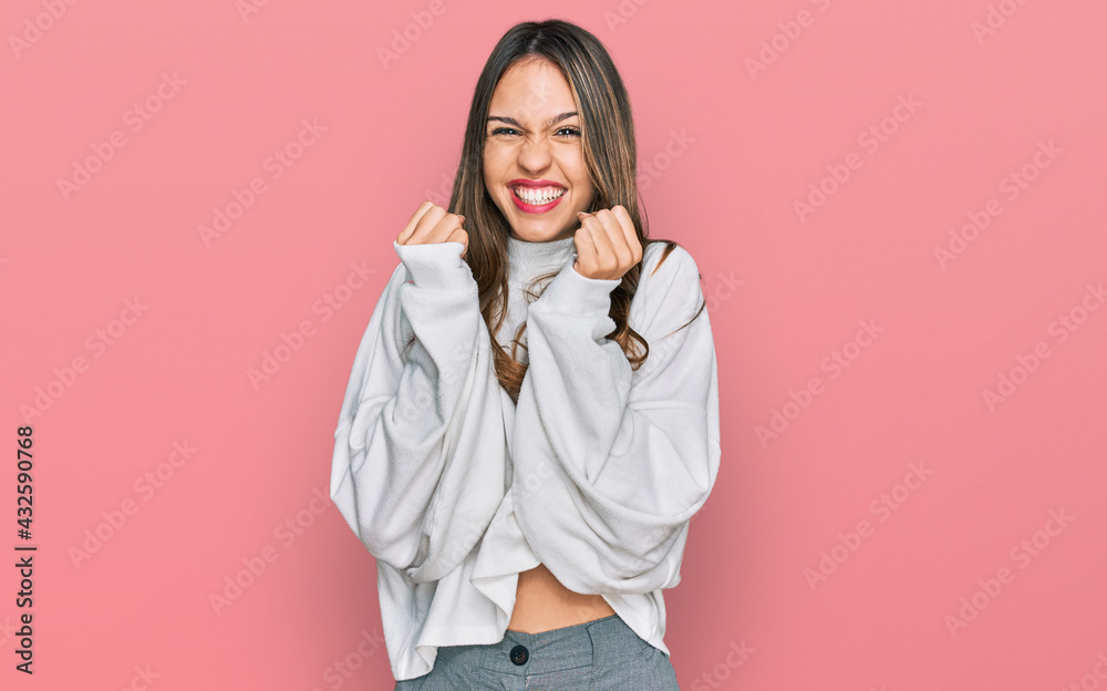 Young brunette woman wearing casual turtleneck sweater celebrating surprised and amazed for success with arms raised and open eyes. winner concept. Young brunette woman wearing casual turtleneck sweater celebrating surprised and amazed for success with arms raised and open eyes. winner concept.
