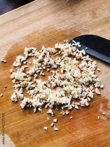 Sliced garlic cloves on wooden chopping Board
