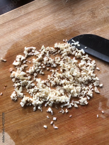 Sliced garlic cloves on wooden chopping Board