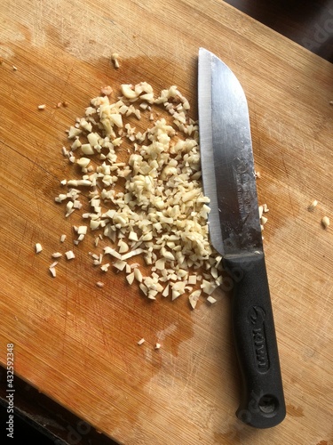 Sliced garlic cloves on wooden chopping Board