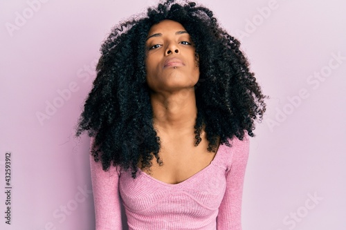 African american woman with afro hair wearing casual pink shirt relaxed with serious expression on face. simple and natural looking at the camera.