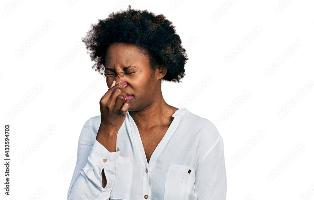 African american woman with afro hair wearing casual white t shirt smelling something stinky and disgusting, intolerable smell, holding breath with fingers on nose. bad smell African american woman with afro hair wearing casual white t shirt smelling something stinky and disgusting, intolerable smell, holding breath with fingers on nose. bad smell