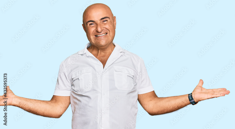 Mature middle east man with mustache wearing casual white shirt smiling showing both hands open palms, presenting and advertising comparison and balance Mature middle east man with mustache wearing casual white shirt smiling showing both hands open palms, presenting and advertising comparison and balance