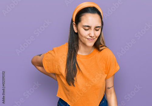 Young hispanic woman wearing casual clothes suffering of backache, touching back with hand, muscular pain © Krakenimages.com