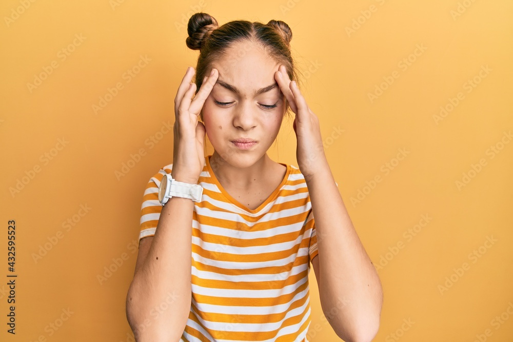 Beautiful brunette little girl wearing casual striped t shirt with hand on head, headache because stress. suffering migraine. Beautiful brunette little girl wearing casual striped t shirt with hand on head, headache because stress. suffering migraine.