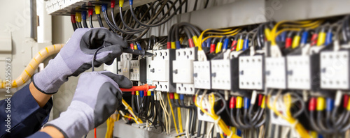 Electrician engineer tests electrical installations and wires on relay protection system. Adjustment of scheme of automation and control of electrical equipment. photo