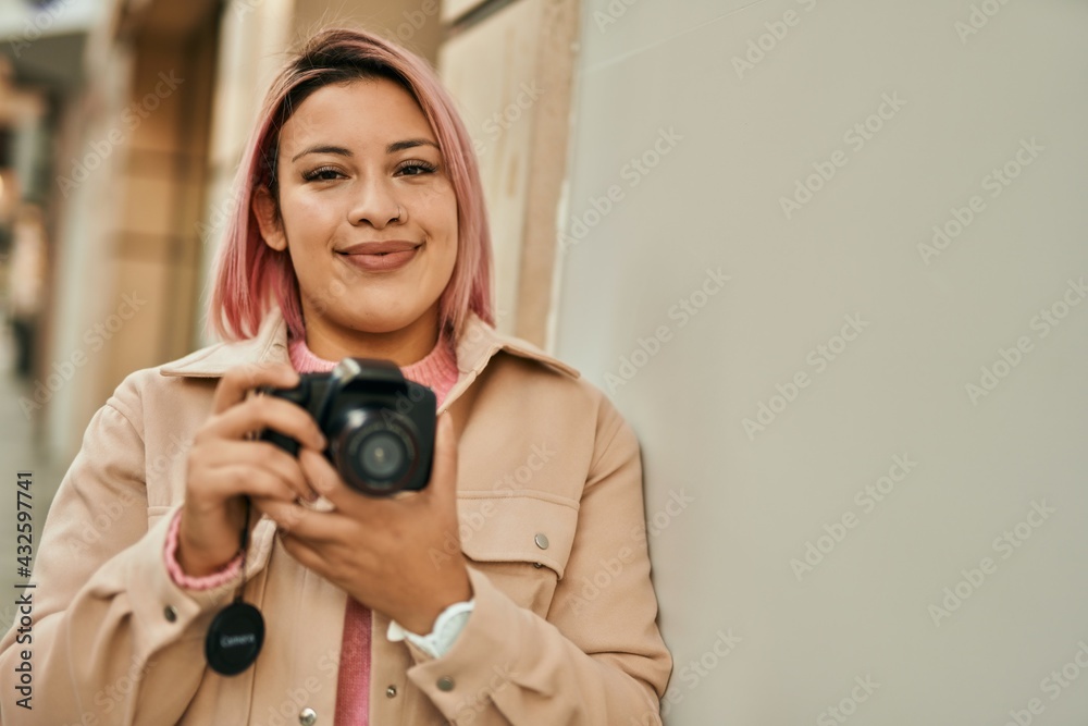 Young hispanic girl smiling happy using reflex camera at the city.